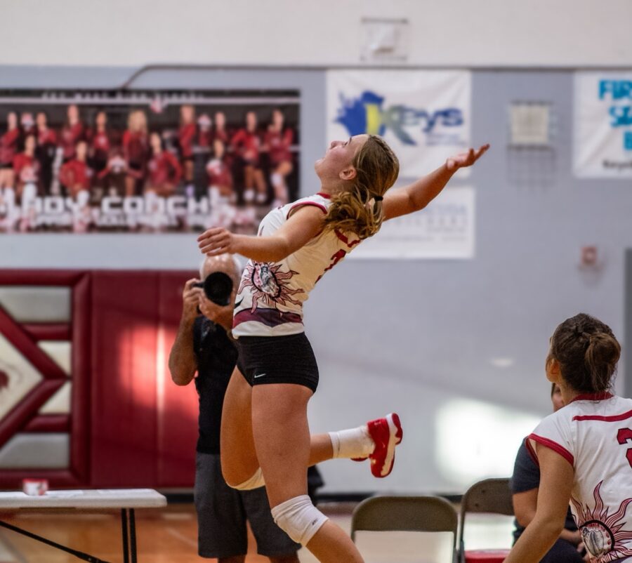 a woman jumping up to hit a volleyball
