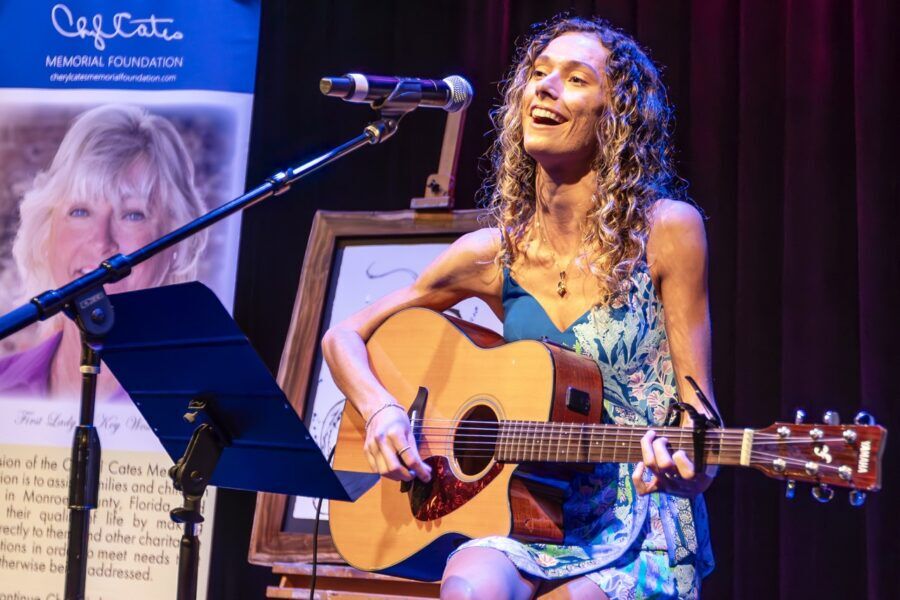 a woman playing a guitar in front of a microphone