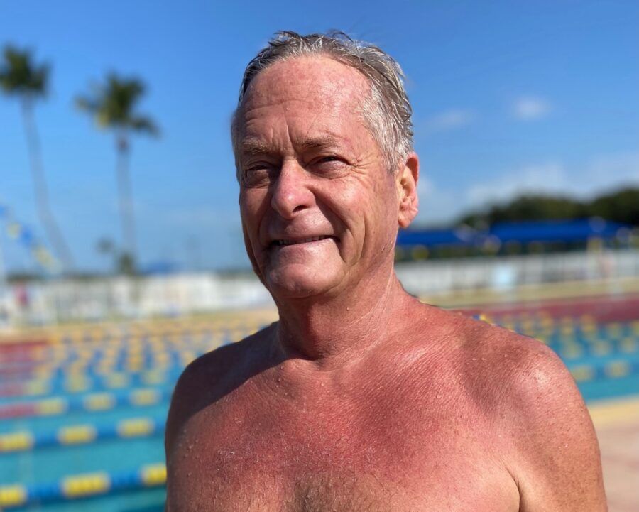 a man without a shirt standing in front of a swimming pool