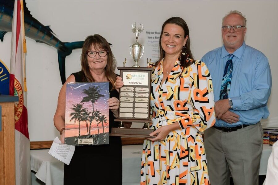 two women and a man holding up a plaque