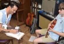 HIP TO THE SCENE: MUSIC IS A COLLABORATIVE EFFORT a man sitting next to a boy with a guitar