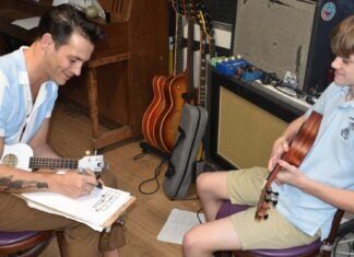 HIP TO THE SCENE: MUSIC IS A COLLABORATIVE EFFORT a man sitting next to a boy with a guitar