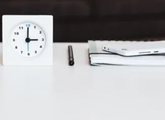 a white clock sitting on top of a white table