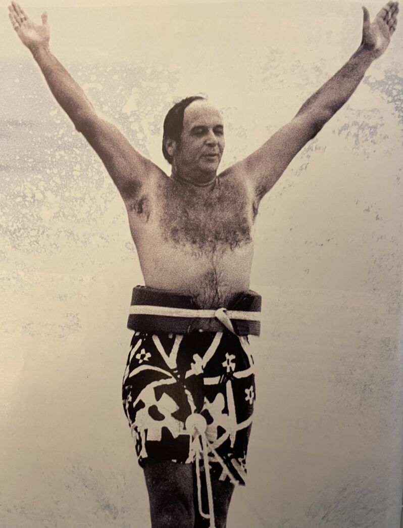 a man standing on a surfboard with his arms in the air