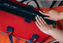 HUMOR: THESE TOP 10 ITEMS ARE ESSENTIALS IN A HURRICANE KIT Close-up of a woman's hands opening a red medical bag, highlighting emergency preparedness.