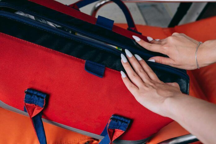 Photo by Mikhail Nilov Close-up of a woman's hands opening a red medical bag, highlighting emergency preparedness.