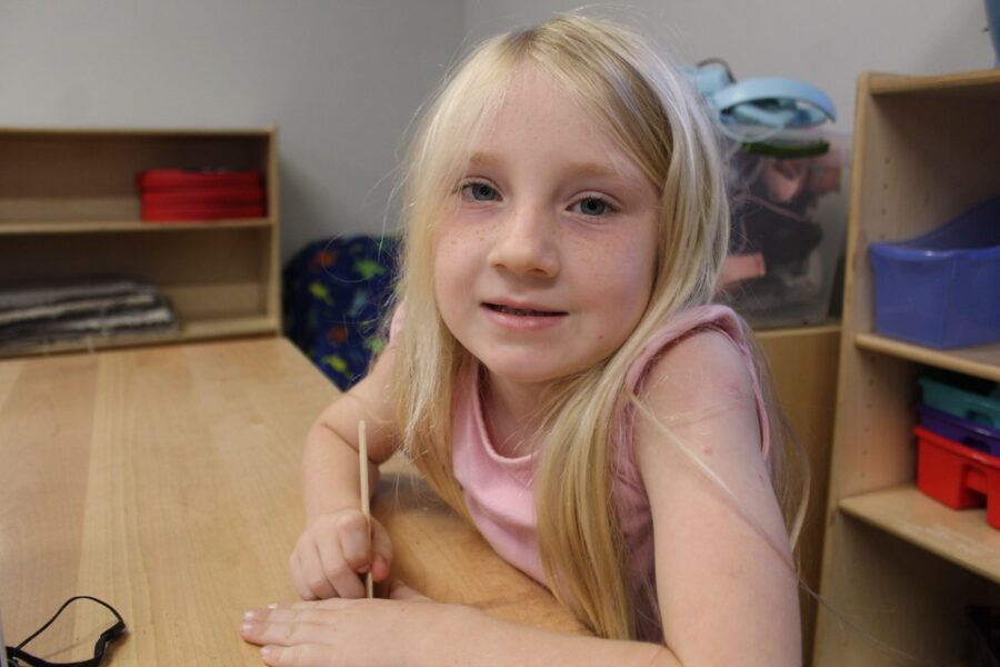 a little girl sitting at a table with a laptop