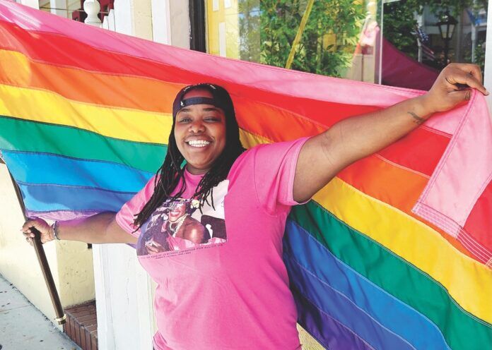 a woman in a pink shirt holding a rainbow flag