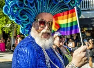 KEY WEST PREPS FOR PRIDE a man in a blue outfit holding a rainbow flag