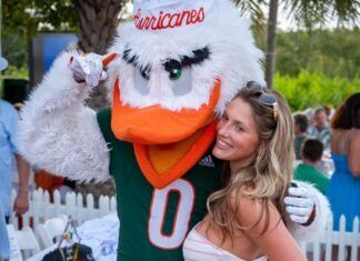CELEBRITIES FROM ‘THE U’ TAKE PART IN FISH TOURNAMENT THIS WEEKEND a woman standing next to a mascot at a party