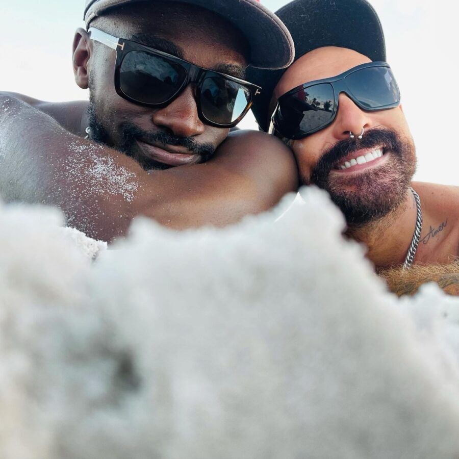 a couple of men laying on top of a sandy beach