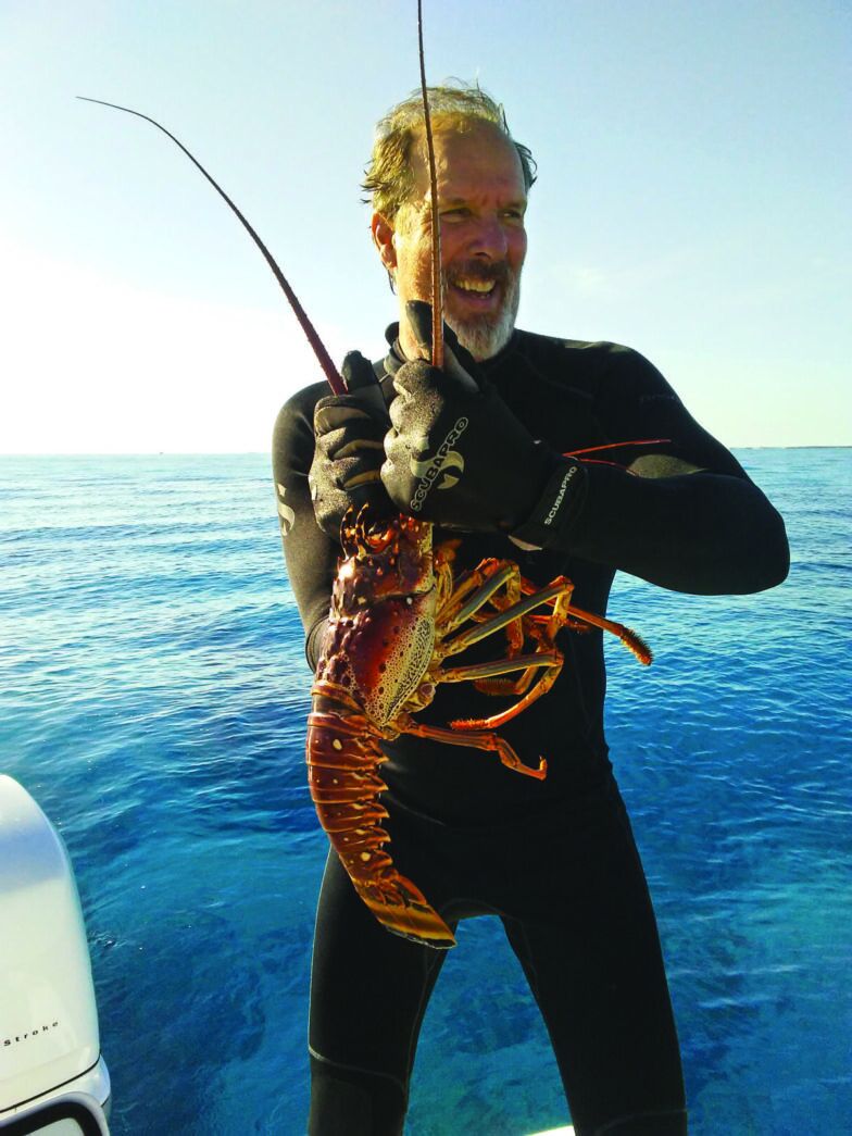 a man on a boat holding a large lobster