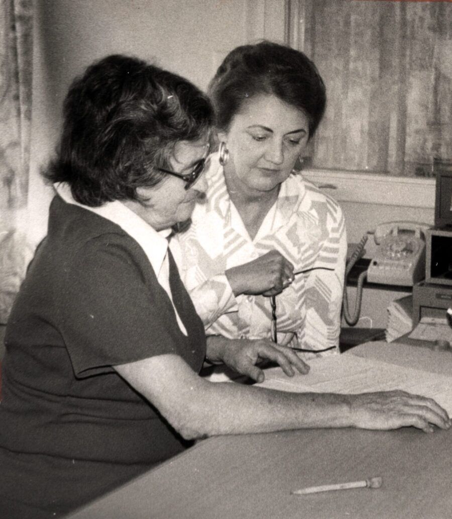 a black and white photo of two women sitting at a table