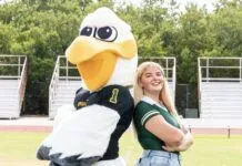 CORAL SHORES ADDS COMPETITIVE CHEER SQUAD FOR 2025-26 a woman standing next to a large bird mascot