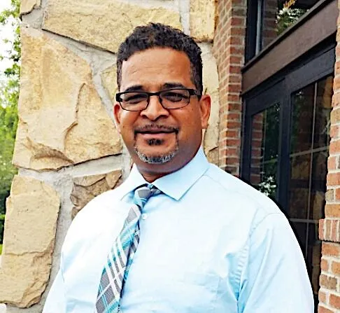 a man wearing glasses and a tie standing in front of a building