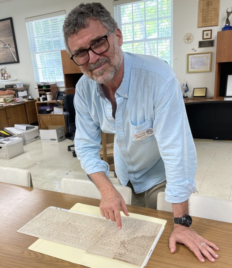 a man standing over a book on top of a wooden table