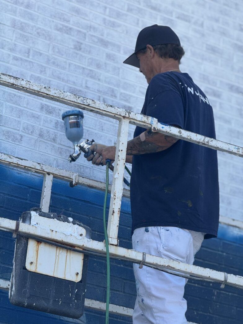 a man painting a building with a paint roller