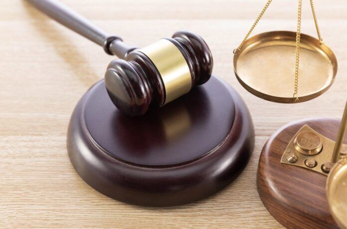 dd a judge's gaven and a scale on a wooden table