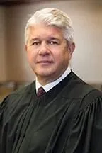 a man in a black robe standing in a room