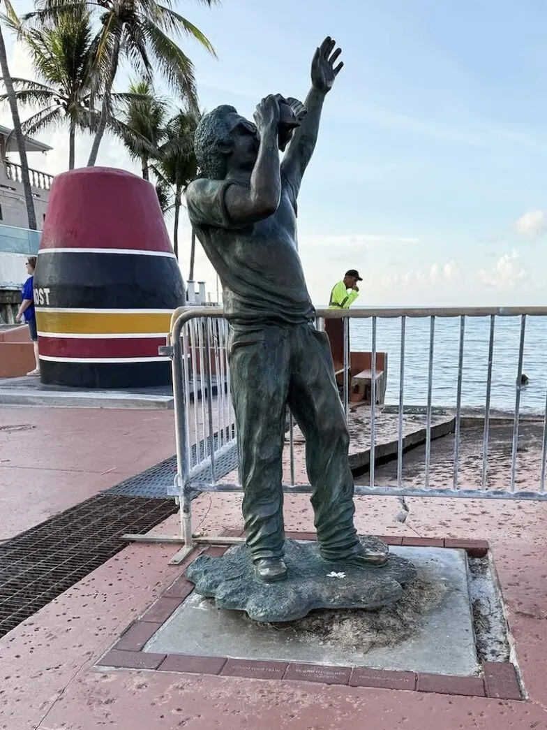 a statue of a boy on a beach next to the ocean