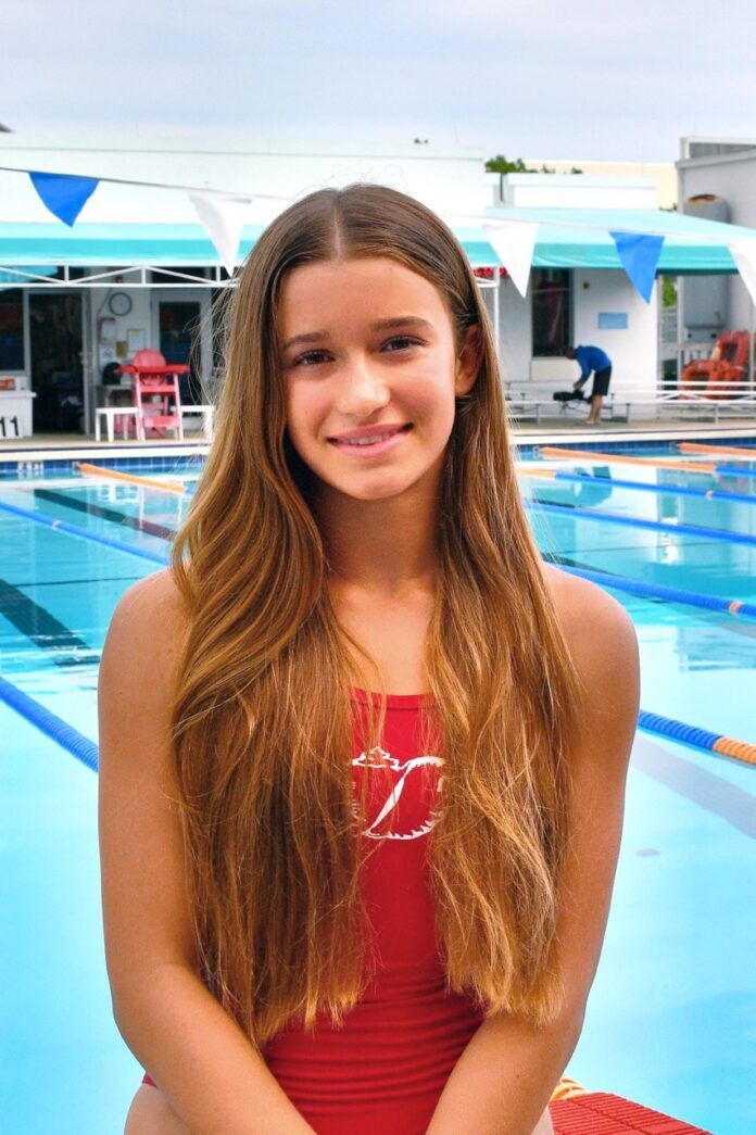 a girl in a red swimsuit standing in front of a swimming pool