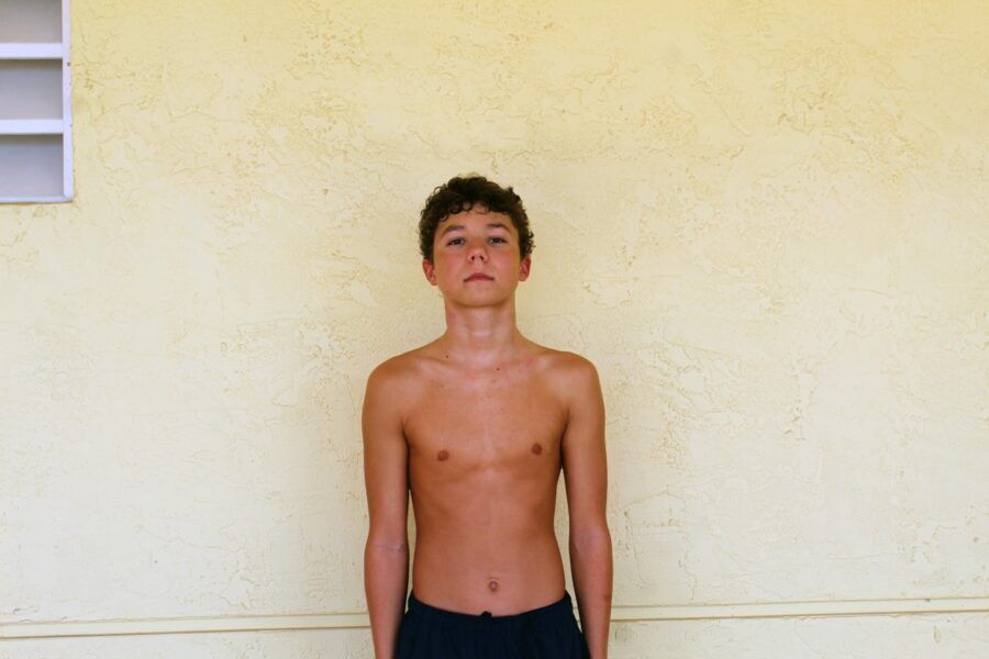 a young boy standing in front of a yellow wall