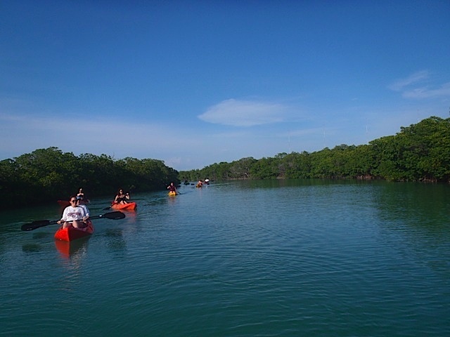 A group of people in a small boat in a body of water - Kayak