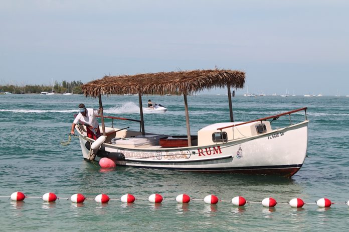 A red and white boat sitting next to a body of water - Fish 'n Fun Boat & Watersports Rentals