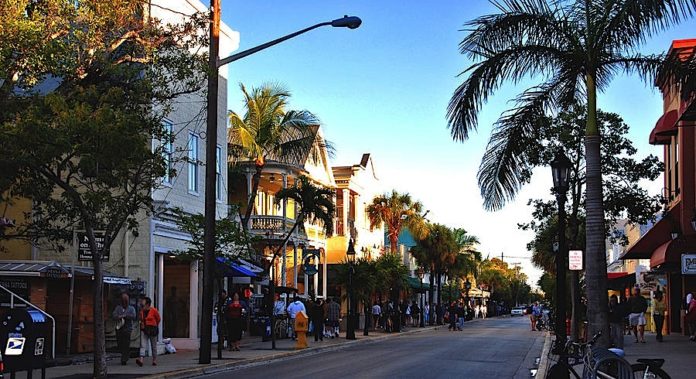 A close up of a busy city street lined with palm trees - Duval Street