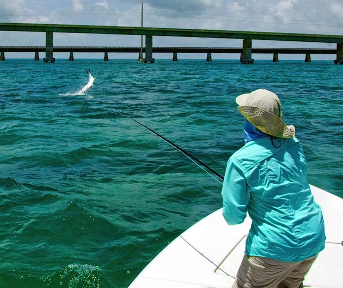 A person standing next to a body of water - Recreational fishing