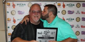 A man holding a sign posing for the camera - Weekly Newspapers