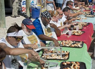 #Events: Amateur eaters to pause for the claws - A group of people standing around a table - Florida stone crab