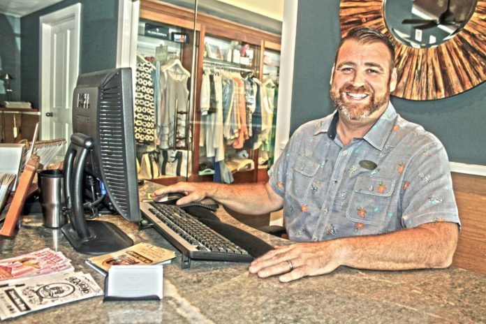 #LoveYourConcierge: Nate Boucree, Ocean Key Resort & Spa - A man sitting at a table with a laptop and smiling at the camera - Flooring