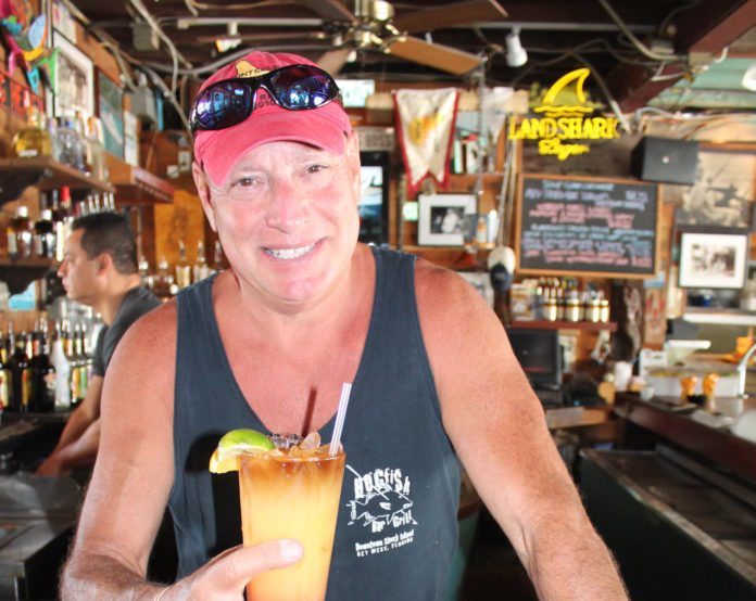 #Libation: Hogfish Bar and Grill - A man holding a sandwich in a restaurant - Beer