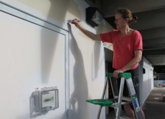 #News: Artist paints mural at Montessori - A man standing in front of a refrigerator - Jean Sport Aviation Center