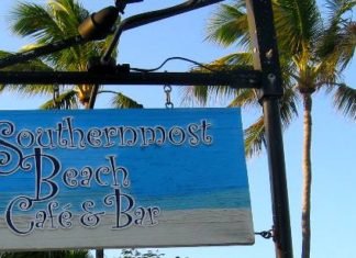 #libation: Cocktails at Southernmost Beach Cafe - A sign on a beach with a palm tree - Palm trees