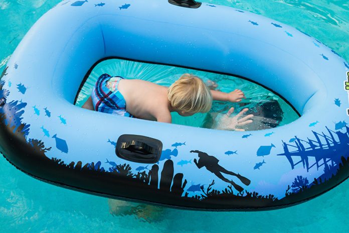 Local inventor designs see-through raft - A person in a blue pool of water - Inflatable boat