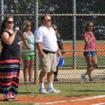 Hit, run, score! Opening ceremonies for MYC baseball season - A group of people standing next to a fence - College softball