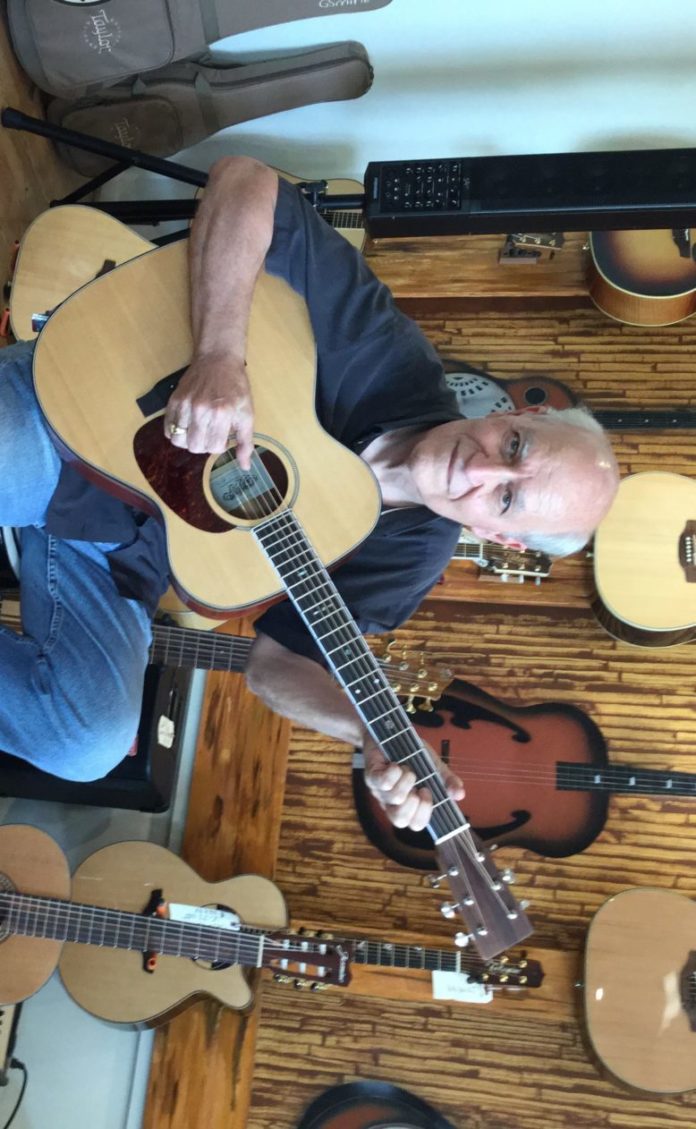Craftsman retires to build guitars - A person holding a guitar - Acoustic guitar