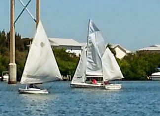 Kids learn to sail at summer camp - A small boat in a body of water - Sail