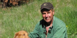 Doctor hears ‘the call’ from abroad - A man holding a large brown dog sitting in the grass - Nova Scotia Duck Tolling Retriever