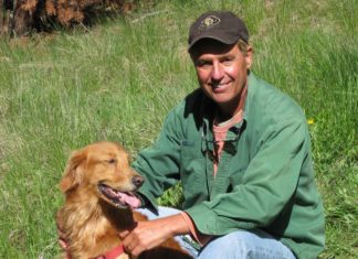 Doctor hears ‘the call’ from abroad - A man holding a large brown dog sitting in the grass - Nova Scotia Duck Tolling Retriever