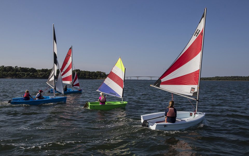Wanted: sailing instructors – Summer sailing program is in the works - A flag on the back of a boat next to a body of water - Sail