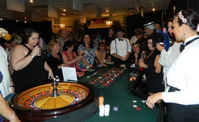 Gambling for Good - A group of people standing around a table - Poker