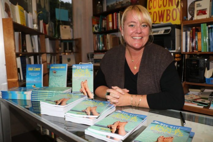 Mandy Miles releases ‘Dos and Don’ts’ - A person sitting at a table in front of a book shelf - Key West