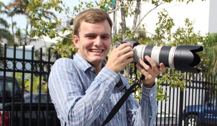 Teen photog is ‘Workin’ for a Livin’’ - A man standing in front of a fence - Photography