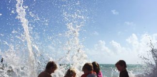 COAST: Live by it - A group of people that are standing in the water - Water