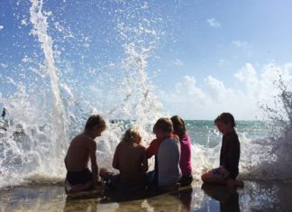 COAST: Live by it - A group of people that are standing in the water - Water