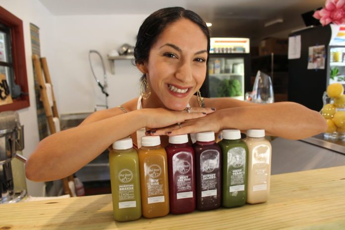 Good Girl Juice & Café opens in Village Square - A person holding a bottle of beer on a table - Good Girl's Juice Bar