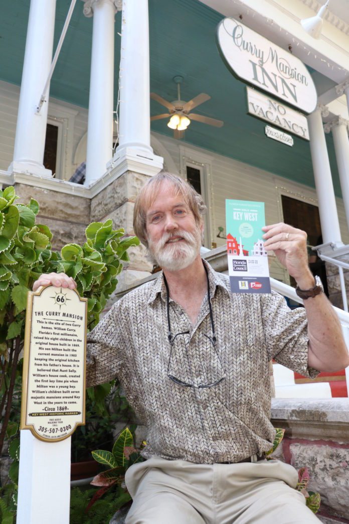 Tour in hand: Free app puts history at fingertips - A person holding a sign in front of a building - Tree